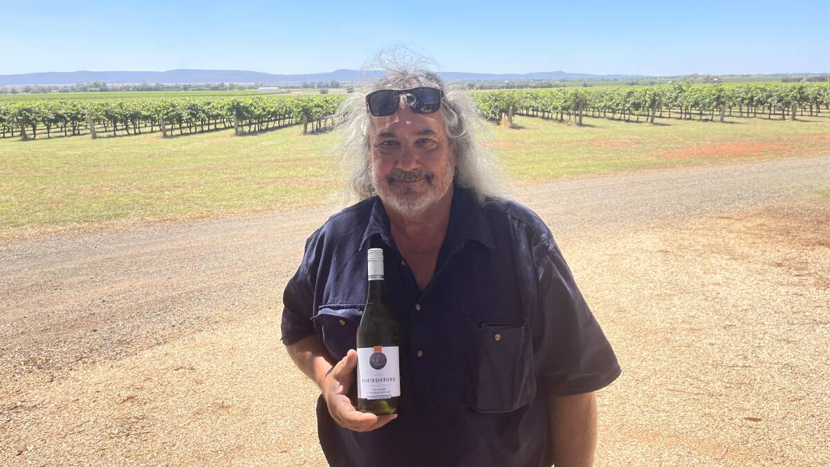 Bob Berton proudly displaying a bottle of Chardonnay from the vines behind him. Picture by Stephen Burns