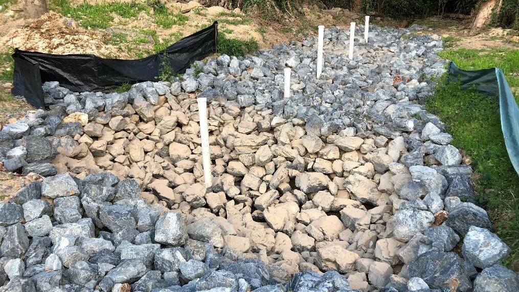 A woodchip "bioreactor" covered in stones to keep it from washing away at Sandy Beach near Woolgoolga. Nitrogen-hungry fungi living in the wood chip mop excess nutrient from blueberry farms previously blamed for high nutrient run-off.