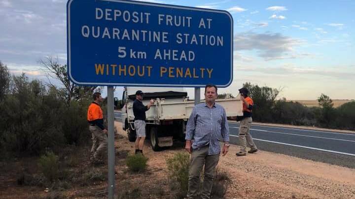 Primary Industries Minister Tim Whetstone with one of the new signs being put up to remind people to dispose of their fruit before reaching the SA border.